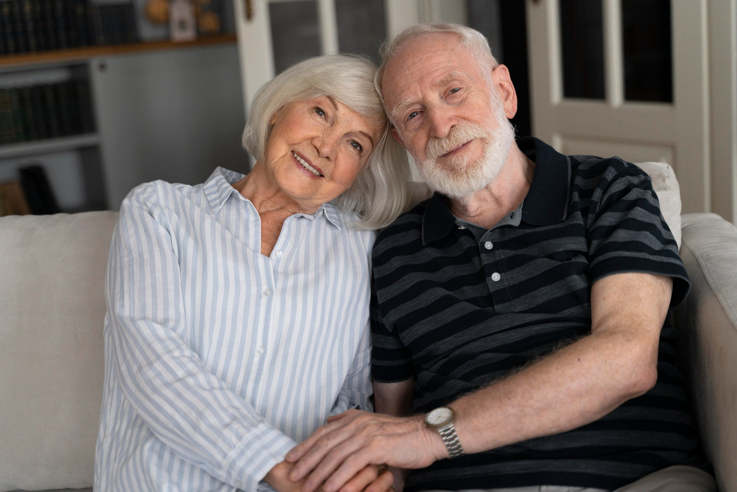 An western australian elderly couple sitting together on a couch, smiling, representing the peace of mind that comes with professional downsizing, decluttering, and removalist services.