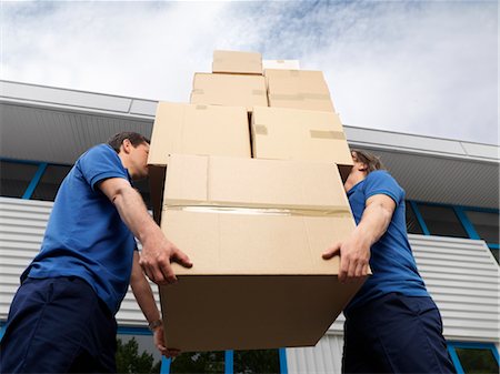  Two removalists carrying a tall stack of boxes, illustrating the efficiency and support provided during downsizing and decluttering processes.